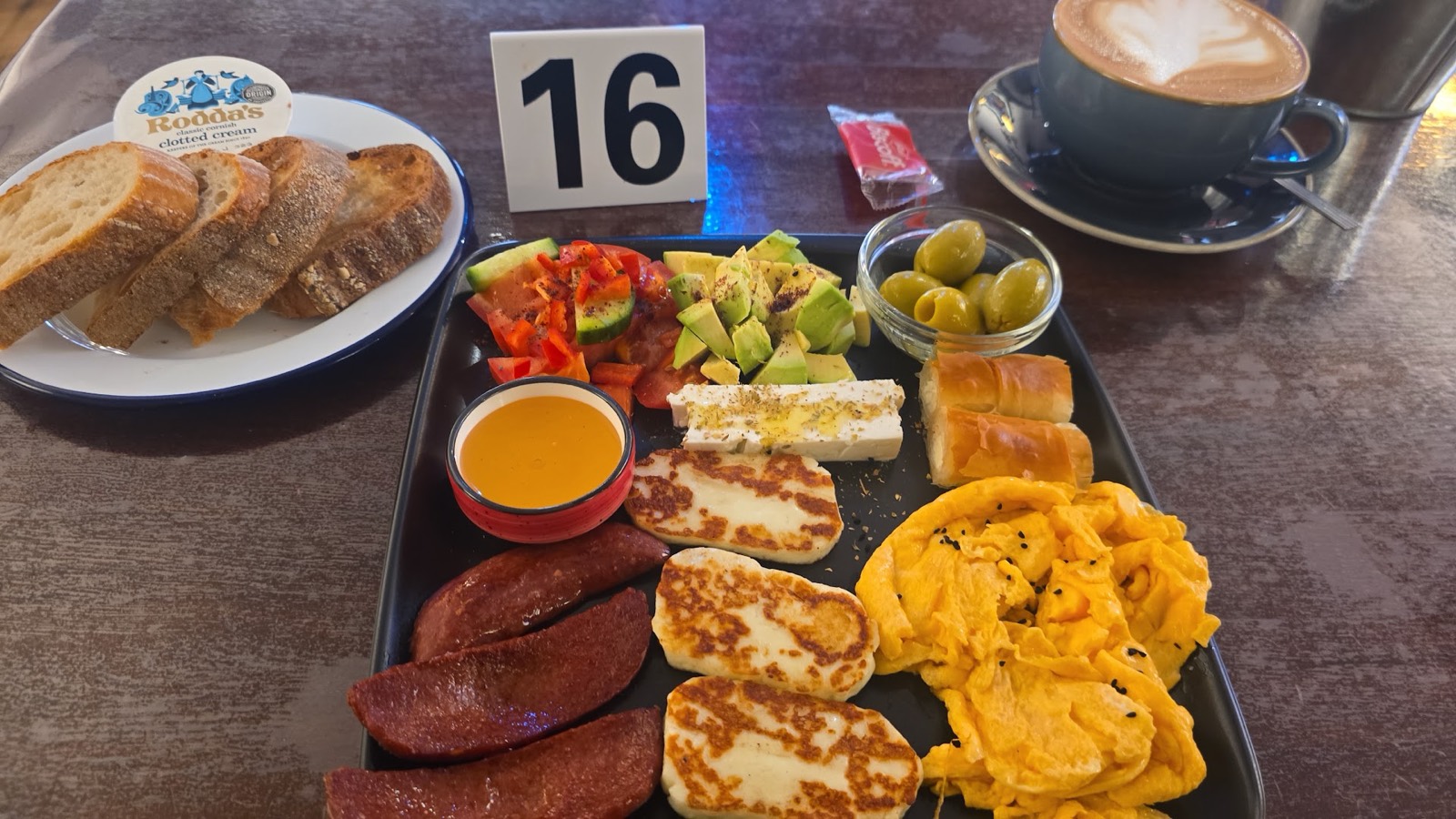 A Mediterranean brunch platter at Mego — grilled halloumi, sujuk, scrambled eggs, feta, avocado, olives and honey with sourdough and a coffee