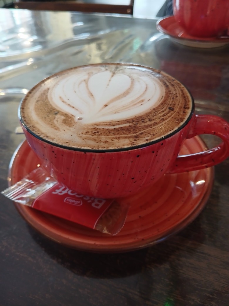 A cappuccino with tulip latte art in Mego's signature red speckled cup and saucer